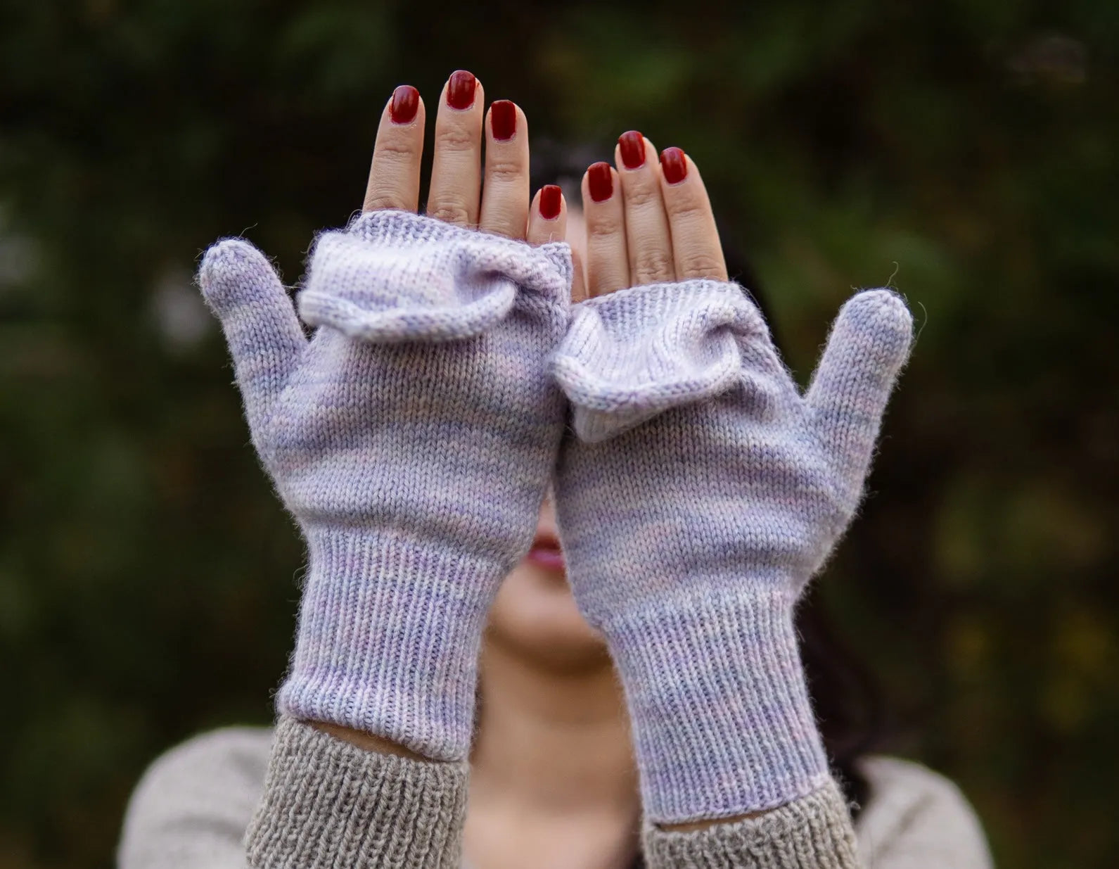 Close-up of light purple pastel convertible mittens with the model's painted nails showing