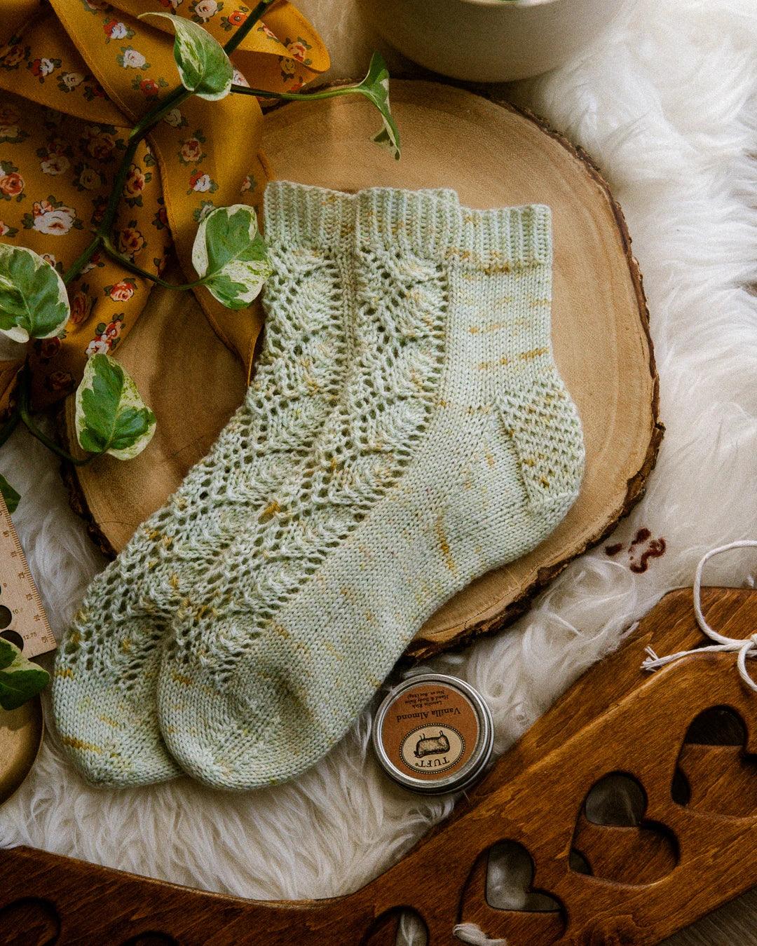 Oolong Socks in a flat lay. This photo features the lace sock knitting pattern with gentle speckle and no ruffle.